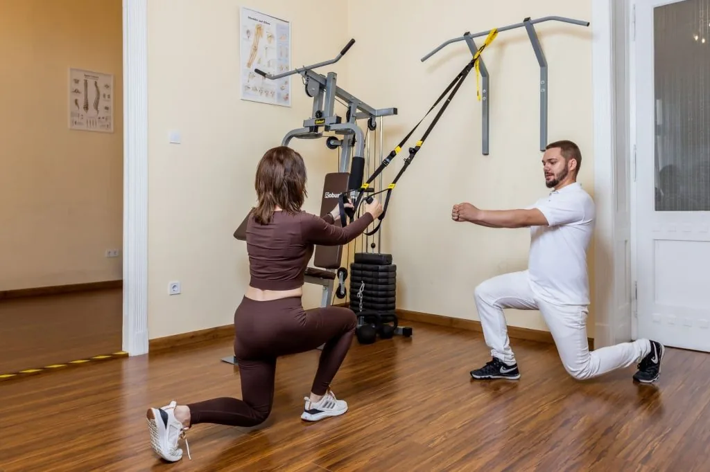 Gyógytornász gépes erősítő gyakorlatot felügyel a budai rendelőben